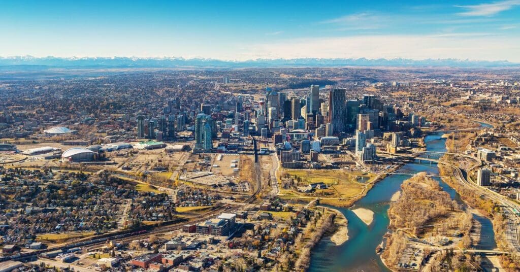 High aerial hero image showing the entire Calgary city landscape, downtown skyscrapers, river pathways, and residential districts, highlighting the best neighbourhoods in Calgary.
