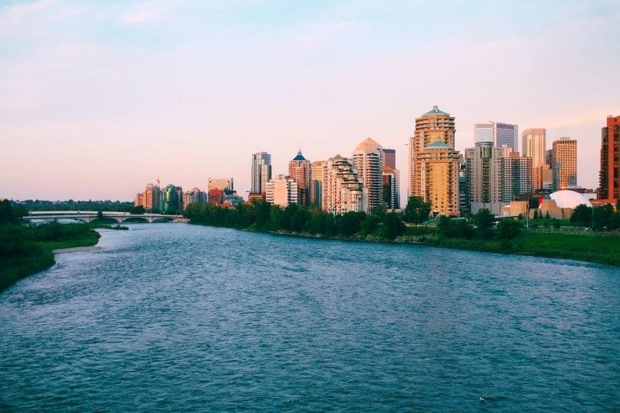 High-rise apartment and condo buildings along the banks of the Bow River in downtown Calgary at dusk.