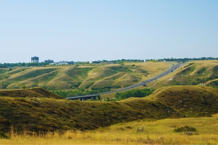 View of Whoop-Up Drive highway winding through the green coulees toward the University of Lethbridge for residents living in Lethbridge, Alberta.