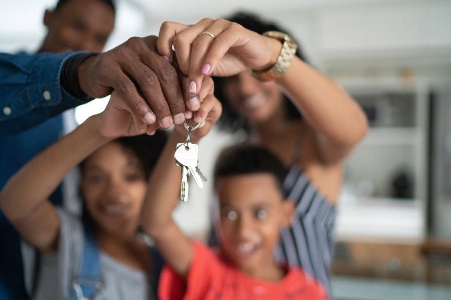 A happy newcomer family holding the keys to their new apartment after being approved for a rental in Canada.